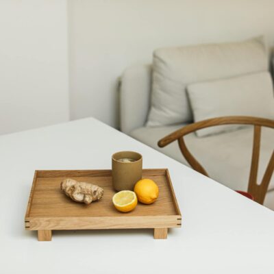 Elegant minimalist composition featuring lemons and ginger on a wooden tray indoors.