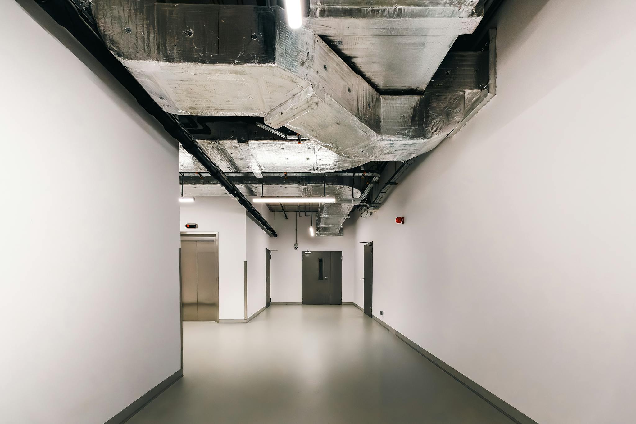 Spacious industrial hallway featuring exposed HVAC ductwork and modern design elements.